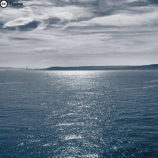 Man blickt über eine sonnenbeschienene Wasserfläche auf eine Küste. Vermutlich handelt es sich um die Dublin Bay in Irland.