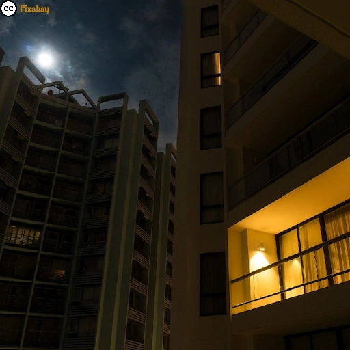 Außenansicht einer beleuchteten Wohnung in einem Hochhaus während der Abenddämmerung.