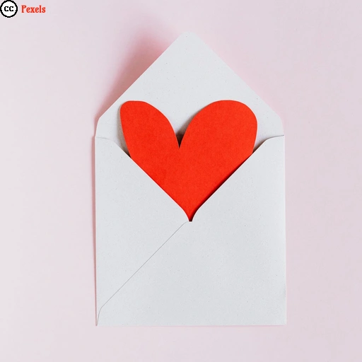 Ein weißer Briefumschlag, in dem ein rotes Herz aus Papier steckt.